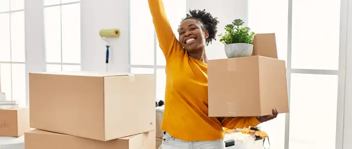Woman cheering as she enters new home with boxes Woman cheering as she enters new home with boxes